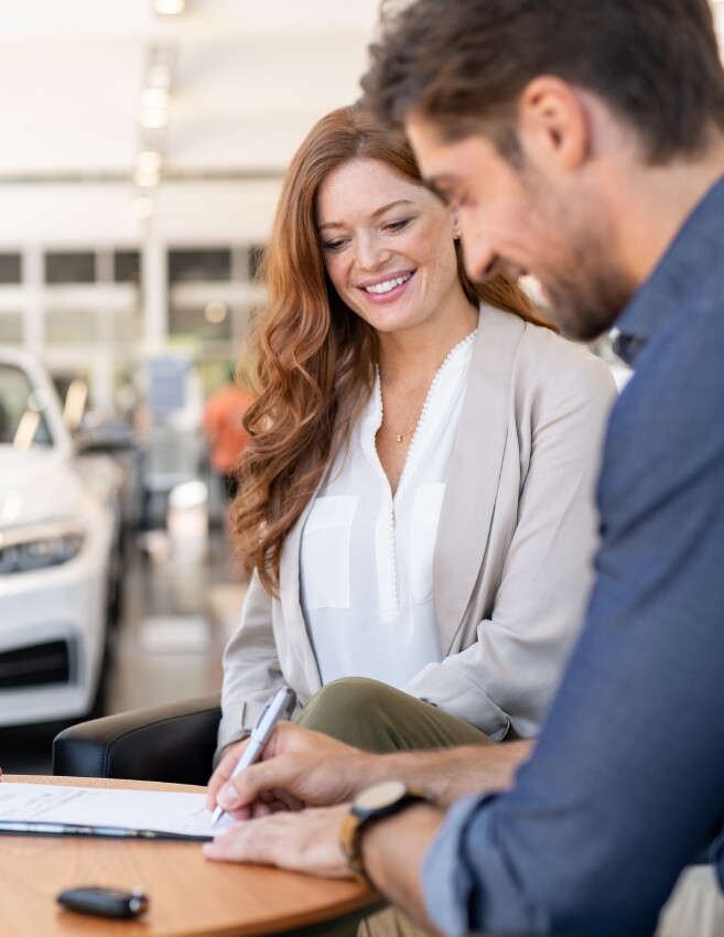 Ein Verkäufer und ein Paar unterzeichnen einen Vertrag im Autohaus